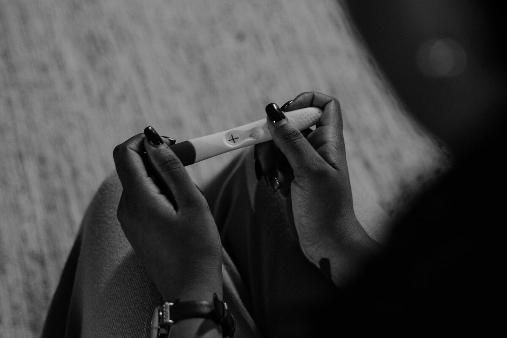 black and white photo of a woman holding a pregnancy test